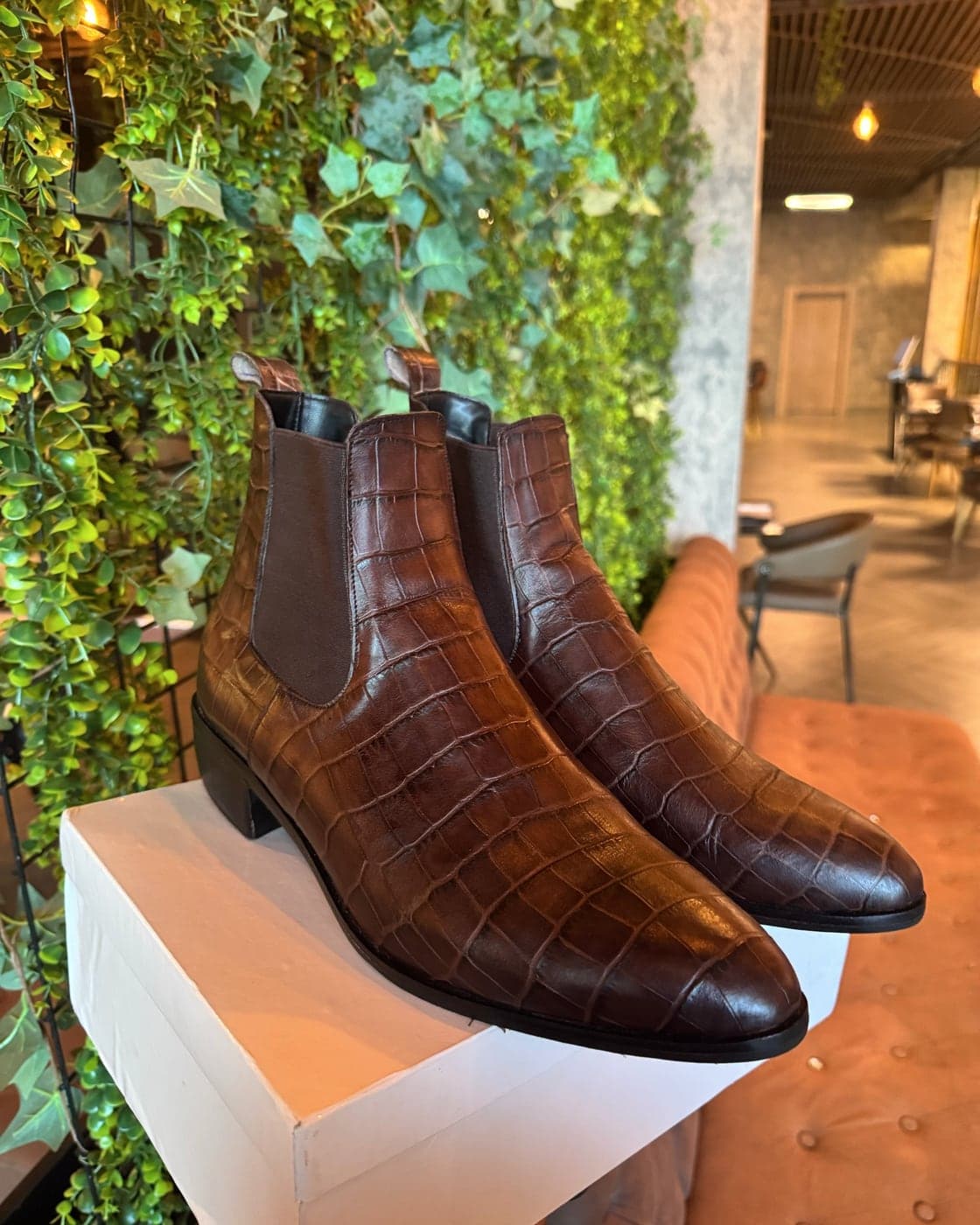 A pair of chestnut croc-embossed leather Chelsea boots standing on a white IRIS Africa box